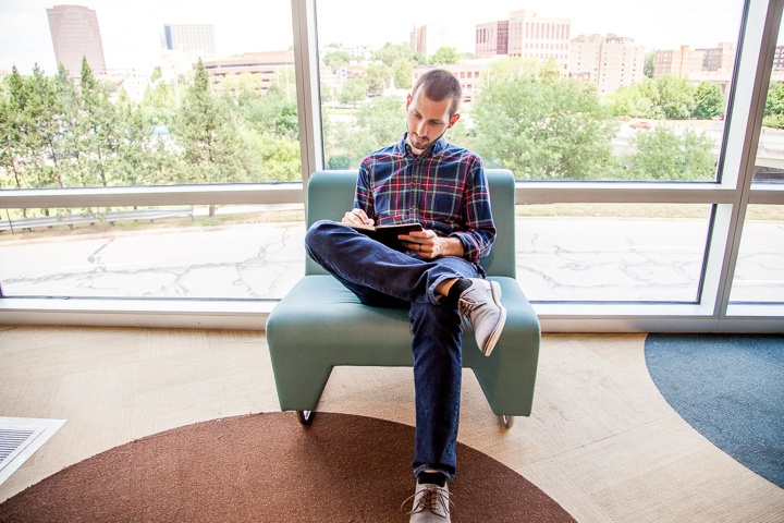 Person sitting in front of a large window working on their computer